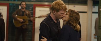 Movie still from “About Time” (2013), directed by Richard Curtis – A man and a woman kissing each other in front of a microphone; Medium shot, Over the shoulder angle