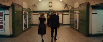 Movie still from “About Time” (2013), directed by Richard Curtis – A man and a woman holding hands while walking down a train platform; Wide shot, Over the shoulder angle