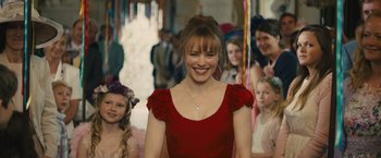 Movie still from “About Time” (2013), directed by Richard Curtis – A woman in a red dress standing in front of a group of people; Medium shot, Over the shoulder angle