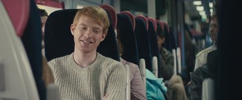 Movie still from “About Time” (2013), directed by Richard Curtis – A man sitting in a row of seats on a train; Medium shot, Over the shoulder angle