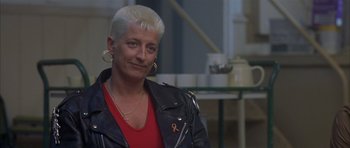 Movie still from “About a Boy” (2002), directed by Chris Weitz – A woman with white hair is smiling for the camera; Close Up shot, Over the shoulder angle