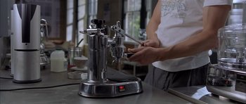 Movie still from “About a Boy” (2002), directed by Chris Weitz – A person using an espresso maker on a table; Extreme Close Up shot, High angle