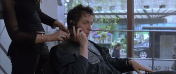 Movie still from “About a Boy” (2002), directed by Chris Weitz – A man talking on a cell phone while getting his hair cut; Close Up shot, Low angle