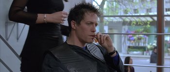 Movie still from “About a Boy” (2002), directed by Chris Weitz – A man sitting in front of a woman talking on a cell phone; Close Up shot, Over the shoulder angle