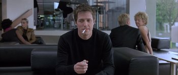 Movie still from “About a Boy” (2002), directed by Chris Weitz – A man smoking a cigarette while sitting on a couch; Medium shot, Low angle