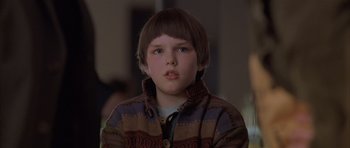 Movie still from “About a Boy” (2002), directed by Chris Weitz – A young boy wearing a sweater and looking at the camera; Close Up shot, Over the shoulder angle