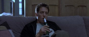 Movie still from “About a Boy” (2002), directed by Chris Weitz – A man sitting on a couch with a beer in his mouth; Close Up shot, Low angle