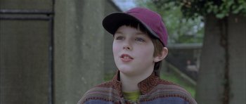 Movie still from “About a Boy” (2002), directed by Chris Weitz – A young boy wearing a purple hat looking up; Close Up shot, Over the shoulder angle