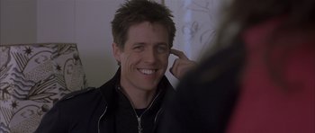 Movie still from “About a Boy” (2002), directed by Chris Weitz – A man smiling while looking at his reflection in a mirror; Close Up shot, Over the shoulder angle
