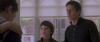 Movie still from “About a Boy” (2002), directed by Chris Weitz – A young boy standing next to a young man in front of a window; Close Up shot, Low angle