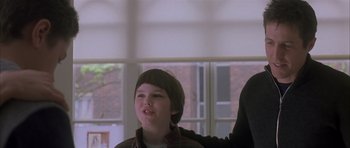 Movie still from “About a Boy” (2002), directed by Chris Weitz – A young boy is smiling at the camera; Medium shot, Low angle