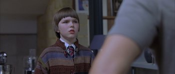 Movie still from “About a Boy” (2002), directed by Chris Weitz – A boy in a suit and tie is looking at a camera; Close Up shot, Over the shoulder angle