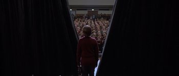 Movie still from “About a Boy” (2002), directed by Chris Weitz – A woman standing in front of a crowd of onlookers; Wide shot, High angle