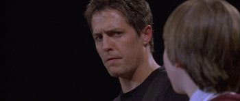 Movie still from “About a Boy” (2002), directed by Chris Weitz – A person wearing a black t - shirt; Close Up shot, Over the shoulder angle