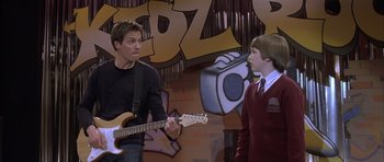 Movie still from “About a Boy” (2002), directed by Chris Weitz – A man and a boy are playing a guitar; Medium shot, Over the shoulder angle