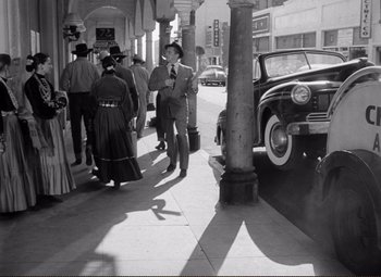Movie still from “Ace in the Hole” (1951), directed by Billy Wilder – A black and white photo of people on the sidewalk; Wide shot, Low angle