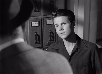 Movie still from “Ace in the Hole” (1951), directed by Billy Wilder – A young man looking into a mirror in a black and white photo; Close Up shot, Over the shoulder angle