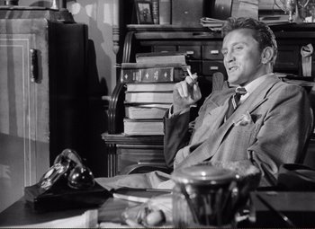 Movie still from “Ace in the Hole” (1951), directed by Billy Wilder – A man sitting at a desk holding a wine glass; Medium shot, Low angle
