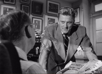 Movie still from “Ace in the Hole” (1951), directed by Billy Wilder – A man in a suit and tie talking to another man in a suit and tie; Medium shot, Over the shoulder angle