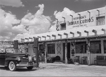 Movie still from “Ace in the Hole” (1951), directed by Billy Wilder – An old truck parked in front of a building; Extreme Wide shot, Low angle