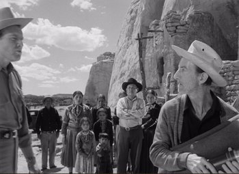 Movie still from “Ace in the Hole” (1951), directed by Billy Wilder – A group of people standing in front of a rock formation; Medium shot, Low angle