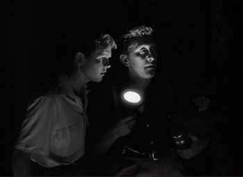 Movie still from “Ace in the Hole” (1951), directed by Billy Wilder – Two young men are looking at a flashlight; Medium shot, Low angle