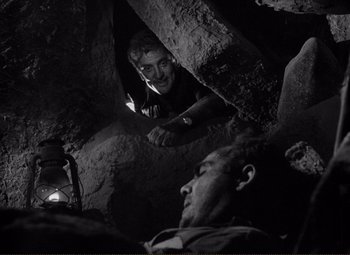 Movie still from “Ace in the Hole” (1951), directed by Billy Wilder – Two men in a cave looking at each other; Medium shot, High angle