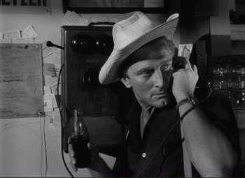Movie still from “Ace in the Hole” (1951), directed by Billy Wilder – A black and white photo of a man holding a bottle of soda; Close Up shot, Low angle