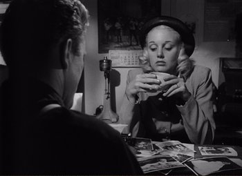 Movie still from “Ace in the Hole” (1951), directed by Billy Wilder – A woman sitting in front of a man holding a cup; Medium shot, Over the shoulder angle