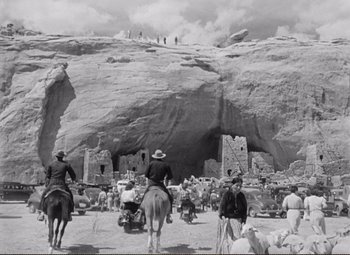 Movie still from “Ace in the Hole” (1951), directed by Billy Wilder – A black and white photo of people on horseback in front of a cave; Extreme Wide shot, Low angle