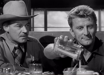 Movie still from “Ace in the Hole” (1951), directed by Billy Wilder – Two men sitting at a table in front of each other; Medium shot, Over the shoulder angle