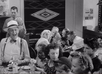 Movie still from “Ace in the Hole” (1951), directed by Billy Wilder – A group of people sitting around a table; Medium shot, Over the shoulder angle