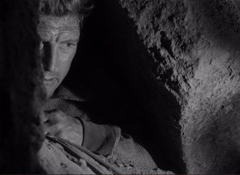 Movie still from “Ace in the Hole” (1951), directed by Billy Wilder – A black and white photo of a man in a cave; Close Up shot, High angle