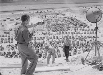 Movie still from “Ace in the Hole” (1951), directed by Billy Wilder – A man standing on top of a building taking a picture of cars; Extreme Wide shot, High angle