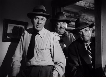 Movie still from “Ace in the Hole” (1951), directed by Billy Wilder – A group of men in hats and ties standing next to each other; Medium shot, Low angle