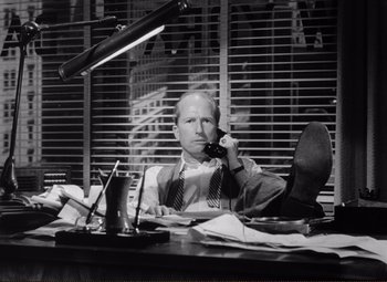 Movie still from “Ace in the Hole” (1951), directed by Billy Wilder – A man sitting at a desk talking on a phone; Medium shot, Low angle
