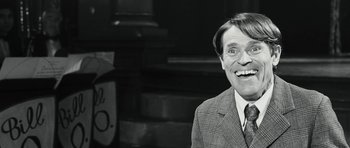 Movie still from “Adam Resurrected” (2008), directed by Paul Schrader – An older man in a suit and tie smiling for the camera; Close Up shot, Over the shoulder angle