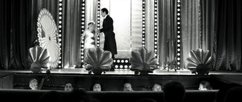 Movie still from “Adam Resurrected” (2008), directed by Paul Schrader – A man and a woman standing on a stage in front of lights; Wide shot, Low angle