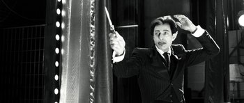 Movie still from “Adam Resurrected” (2008), directed by Paul Schrader – A black and white photo of a man in a suit and tie holding a knife; Medium shot, Low angle