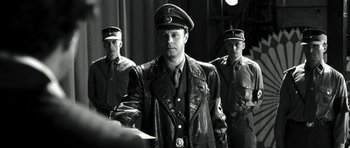 Movie still from “Adam Resurrected” (2008), directed by Paul Schrader – A black and white photo of a man in a military uniform; Medium shot, Over the shoulder angle