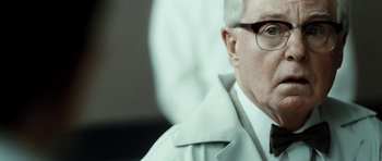 Movie still from “Adam Resurrected” (2008), directed by Paul Schrader – An older man wearing glasses and wearing a white coat; Close Up shot, Over the shoulder angle