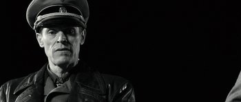 Movie still from “Adam Resurrected” (2008), directed by Paul Schrader – A man in a leather jacket and a hat; Close Up shot, Low angle
