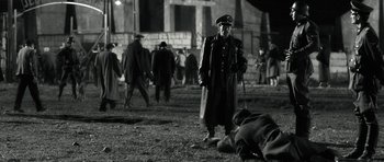 Movie still from “Adam Resurrected” (2008), directed by Paul Schrader – An old man in a military uniform standing next to a dead body; Wide shot, Low angle