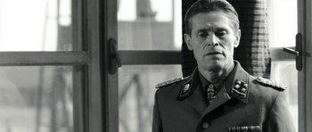 Movie still from “Adam Resurrected” (2008), directed by Paul Schrader – A man in a military uniform standing in front of a window; Close Up shot, Over the shoulder angle
