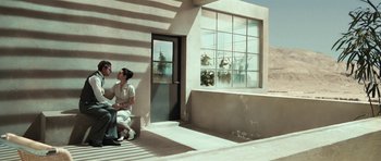 Movie still from “Adam Resurrected” (2008), directed by Paul Schrader – A man and a woman sitting in front of a building; Wide shot, Low angle