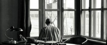 Movie still from “Adam Resurrected” (2008), directed by Paul Schrader – An old man sitting at a table looking out a window; Medium shot, Over the shoulder angle