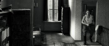 Movie still from “Adam Resurrected” (2008), directed by Paul Schrader – A black and white photo of a living room with a window; Wide shot, High angle