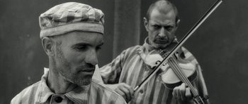 Movie still from “Adam Resurrected” (2008), directed by Paul Schrader – Two men in striped shirts playing a musical instrument; Close Up shot, Over the shoulder angle