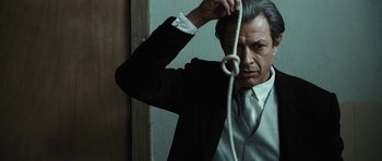 Movie still from “Adam Resurrected” (2008), directed by Paul Schrader – A man in a suit and tie holding onto a rope; Close Up shot, Low angle