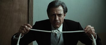 Movie still from “Adam Resurrected” (2008), directed by Paul Schrader – A man in a suit and tie holding onto a rope; Close Up shot, Low angle